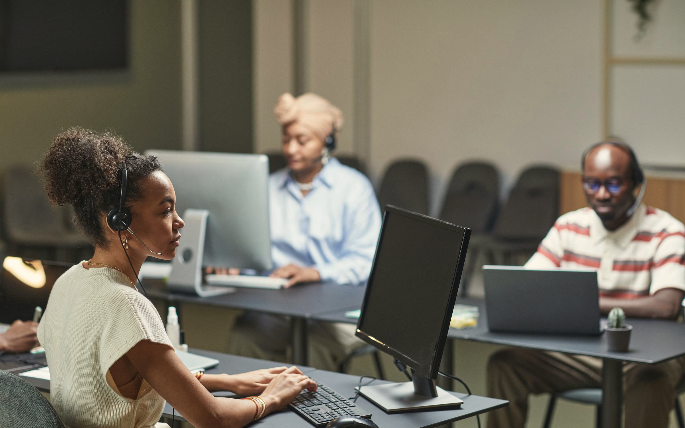 People wearing headsets work at computers in an open plan service centre